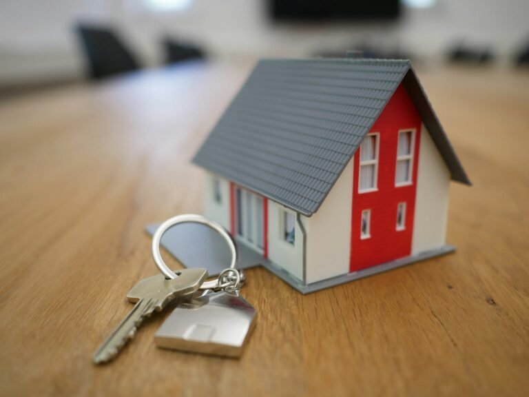 Miniatura de casa sobre mesa com documentos de imóvel