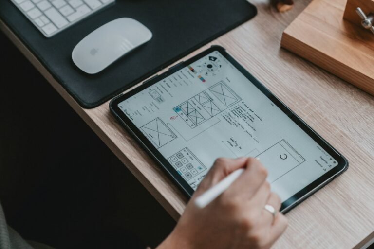 Mão desenhando wireframes de interface em tablet com caneta digital