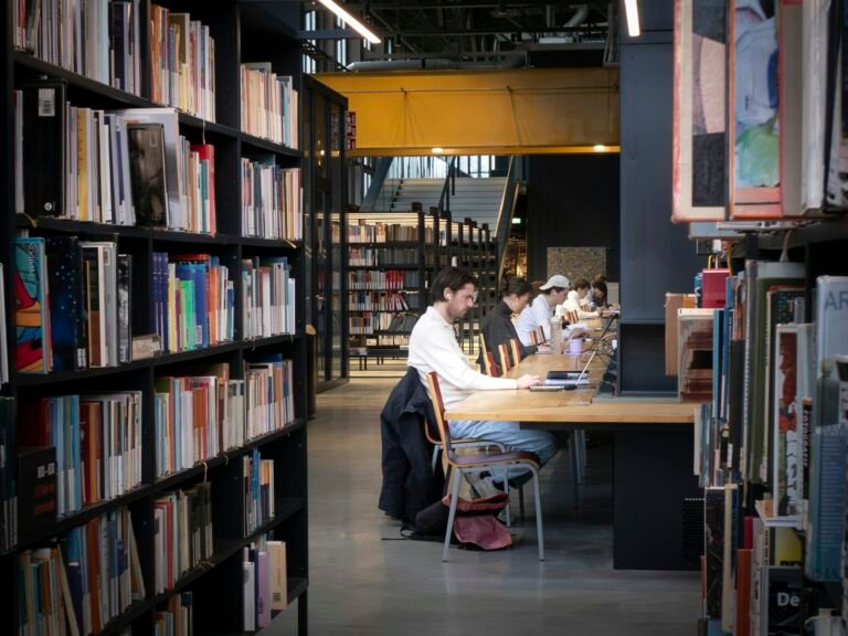 Estudantes estudando em mesas de uma biblioteca