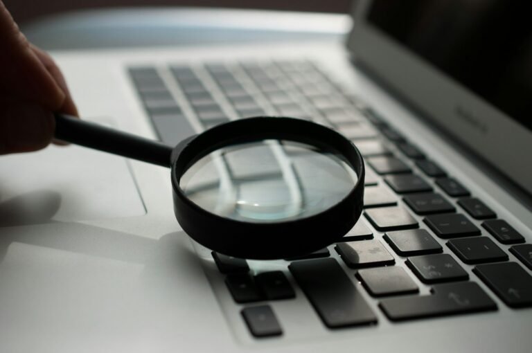Lupa sobre documentos ao lado de computador