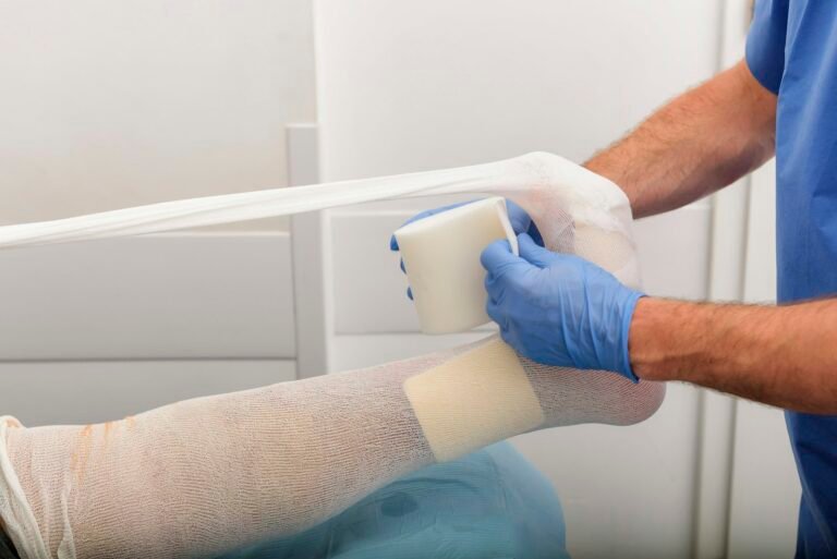 Profissional aplicando bandagem de imobilização no pé de um paciente